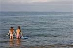 Brother and sister paddling in sea