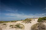 Brother and sister running over sand dunes