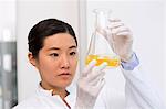 Female scientist examining bacterial growth in flask containing LB (Lysogeny broth) medium