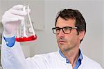 Male scientist examining ph-reaction of liquid in flask