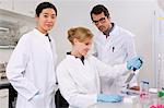 Group of scientists testing in laboratory, pipetting solution