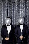 Portrait of two young men with balloons in front of faces