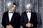 Two young men hiding behind balloons