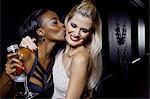 Two female friends hugging and kissing in nightclub