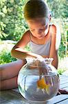 Young girl with fingers in goldfish bowl