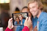 Group of friends in cafe photographing with digital tablet