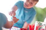 Two young sisters behind stall selling drink to cousin