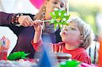 Young boy blowing windmill at birthday party