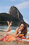 Woman on beach writing postcard, Rio de Janeiro, Brazil