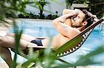 Man reclining on sunlounger by swimming pool