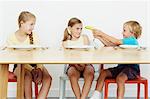 Three children at table, boy holding banana