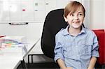 Boy wearing blue shirt on office chair