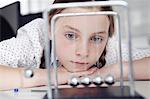 Girl playing with newton's cradle on desk