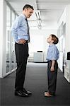 Father and son standing face to face in office