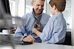 Son putting tie on father at desk