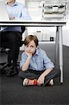 Boy sitting on floor with businessman working at desk