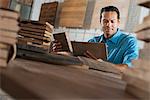 A Young Man In A Workshop. Examining A Reclaimed Wood Sample.