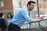 Business People Outdoors. A Latino Businessman In Shirt And Tie, Leaning On A Railing. Relaxing.