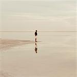 A Man Standing At The Edge Of The Flooded Bonneville Salt Flats At Dusk.