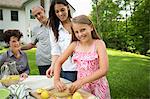 A Summer Family Gathering At A Farm. A Girl Slicing And Juicing Lemons To Make Lemonade.