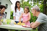 A Summer Family Gathering At A Farm. A Girl Slicing And Juicing Lemons To Make Lemonade.