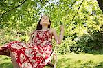 Summer. A Girl In A Sundress On A Swing Suspending From The Branches Of A Tree.