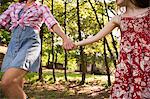 A Woman And A Young Girl Holding Hands And Running Along Under The Trees.