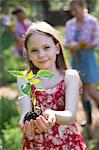 Garden. A Young Girl Holding A Young Plant With Green Foliage And A Healthy Rootball In Her Hands.