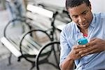 Summer In The City. A Man Sitting On A Bench Using A Smart Phone.