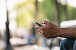 Summer. A Man Sitting On A Bench Using A Smart Phone.