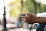 Summer. A Man Sitting On A Bench Using A Smart Phone.