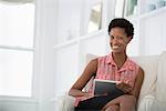 Office Life. A Woman Sitting On A Sofa, Using A Digital Tablet.