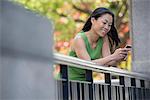 A Woman In A Green Dress Outdoors In A City Park Under Trees In Blossom.