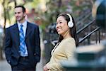 A Woman Wearing Music Headphones, And A Man In A Business Suit.