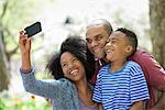 Two Adults And A Young Boy Taking Photographs With A Smart Phone.