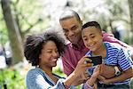 A Family In The Park On A Sunny Day. Taking Photographs With A Smart Phone.