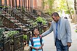 An Adult And A Child, A Father And Son, Walking Together On The Street In The City.