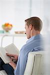 Business. A Man Sitting Holding A Book In His Hands. Reading. Focussing On The Page. Back View.