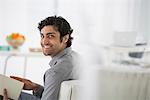 Business. A Man Sitting Holding A Book In His Hands. Turning Around And Smiling.