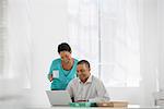 Business. A Woman With A Cup Of Coffee And A Man Looking At A Laptop.