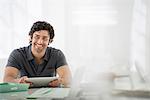 Business. A Light Airy Office Environment. A Man Sitting Holding A Digital Tablet.