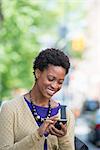 City. A Woman In A Purple Dress Checking Her Smart Phone.