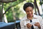 City. A Woman Outdoors In The Park, Checking Her Smart Phone.