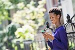 City. A Woman In A Purple Dress Checking Her Smart Phone.