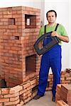 Mason building a traditional stove from red clay bricks - holding the door