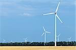 Wind turbine farm stretching above land used for agriculture