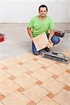 Worker laying floor tiles on concrete surface in a new building