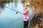 beautiful blond girl in pink sweater fishing