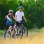 Young Happy Couple Riding Mountain Bikes Outdoor. Healthy Lifestyle Concept
