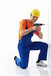 Builder in helmet with a drill on a white background